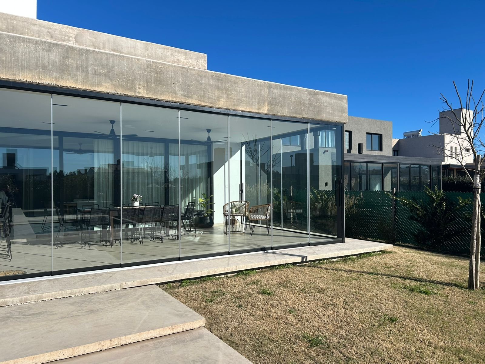 Fachada moderna con amplios ventanales y hormigón visto — proyecto CHACRAS DE LA VILLA, por GARCIA RECTA DESIGN, en X5105 Villa Allende